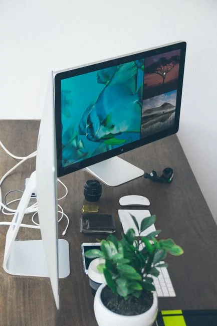 A sleek office desk setup featuring Apple devices: iMac, MacBook, and iPad.